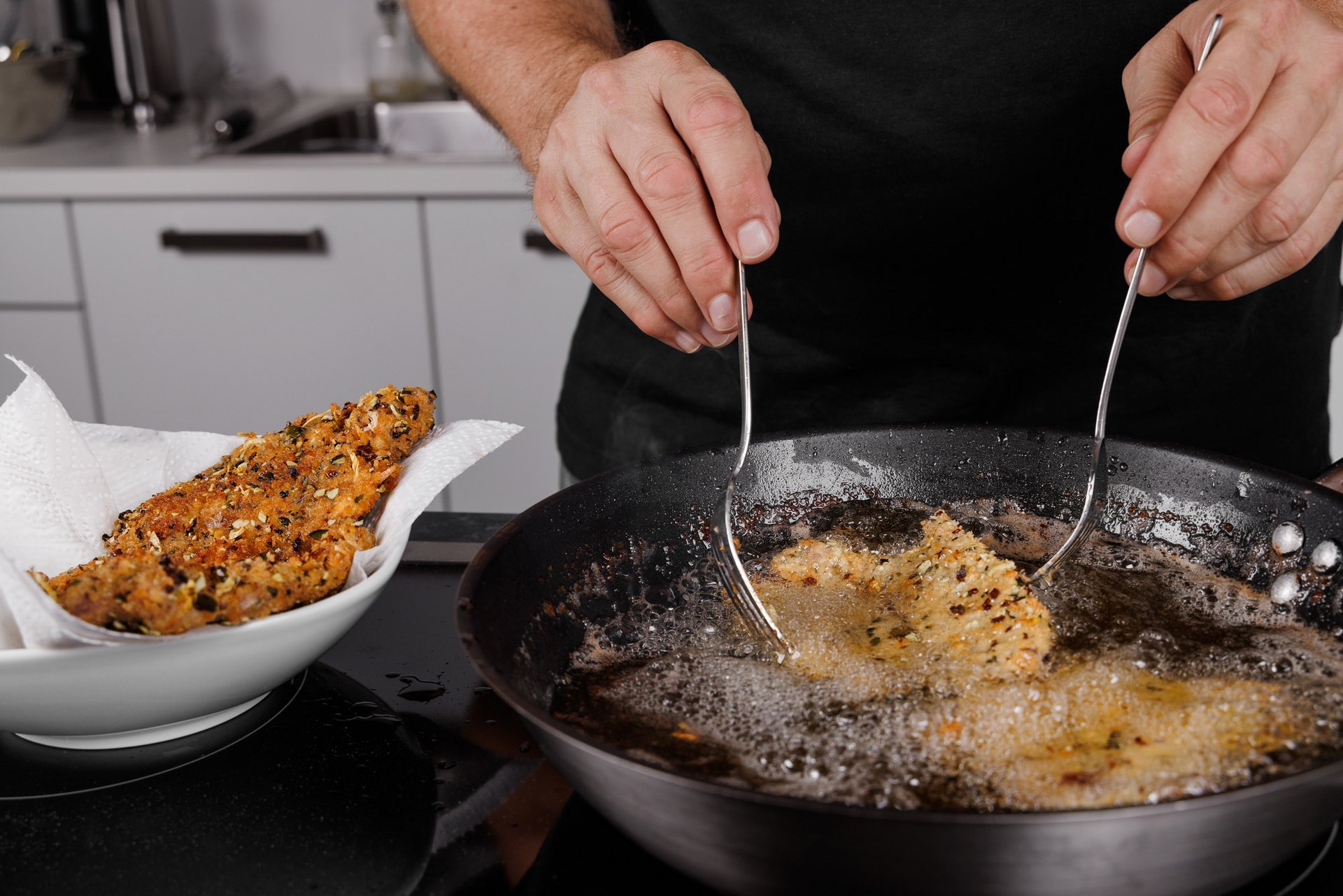 Panierte Speisen werden in einer Pfanne in heißem Öl ausgebacken – Foodfotografie beim Zubereitungsprozess