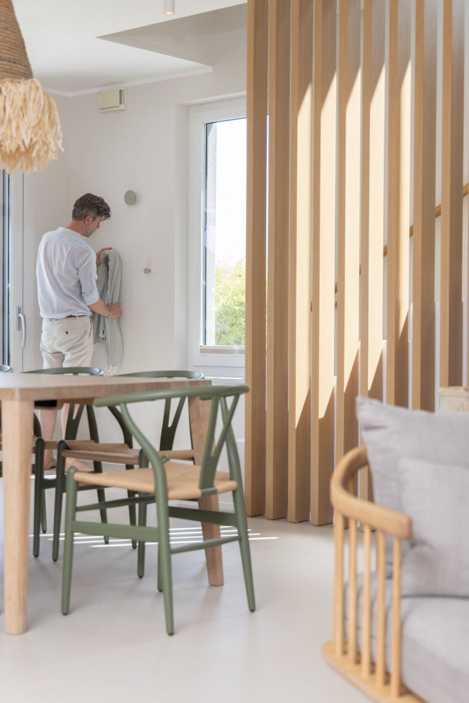 Interior Designer Christian Hantschel richtet beim Fotoshooting eine Decke am Wandhaken neben dem Esstisch